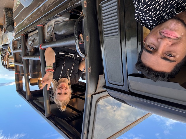 Guest and guide smiling from a safari jeep
